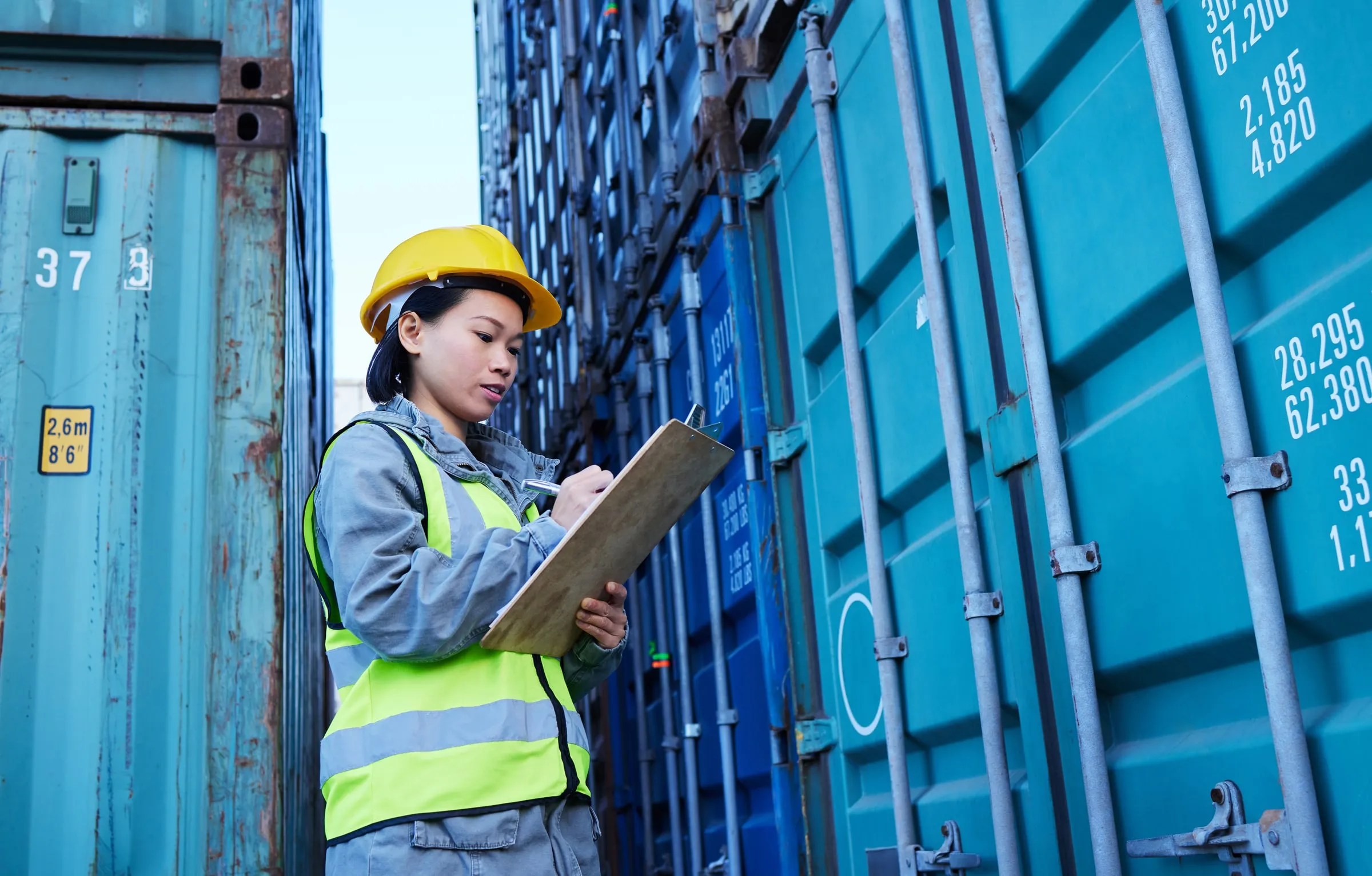 Inspectora revisando documentación frente a contenedores en una terminal de carga