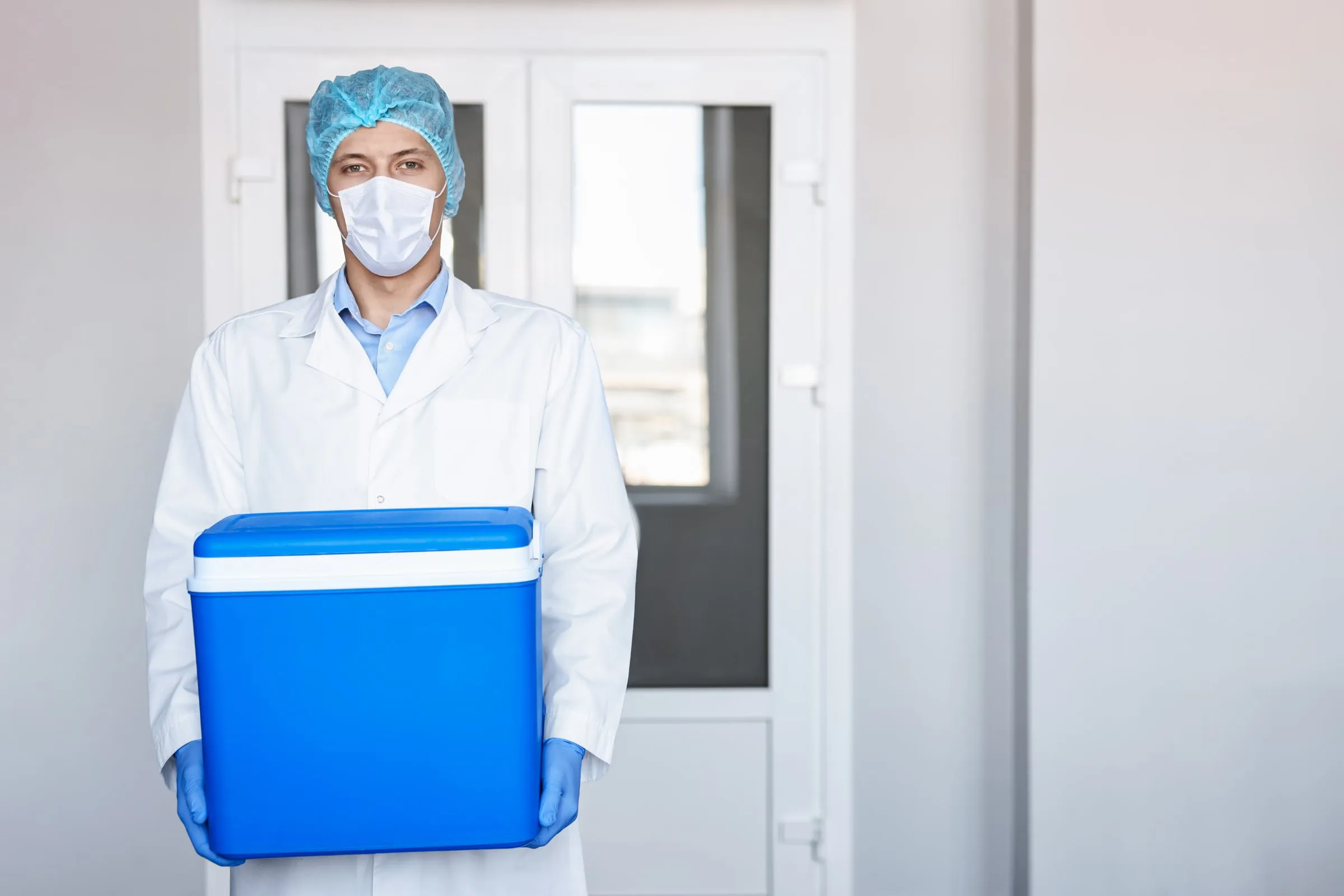 Profesional de laboratorio trasladando un contenedor térmico con muestras médicas